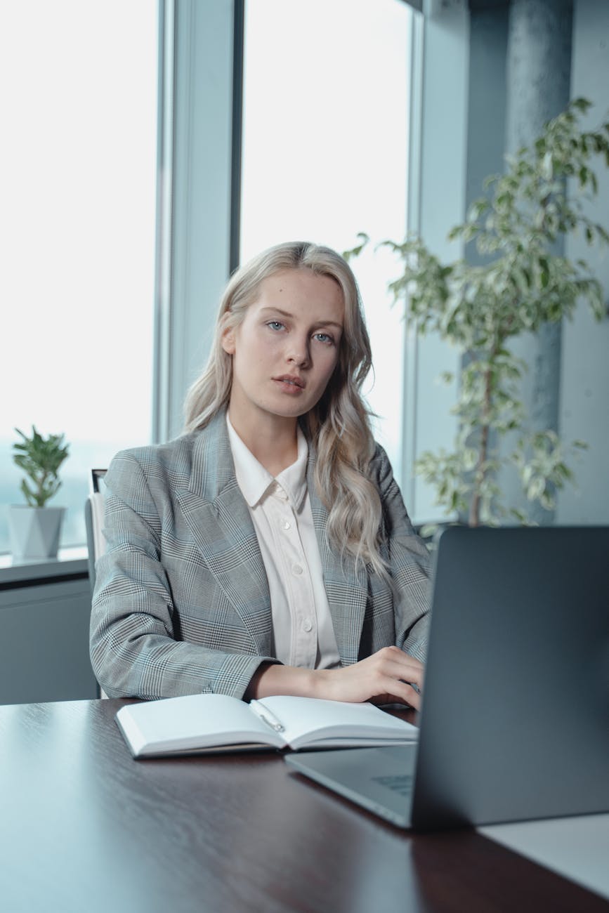 woman in gray blazer sitting by the table with laptop computer