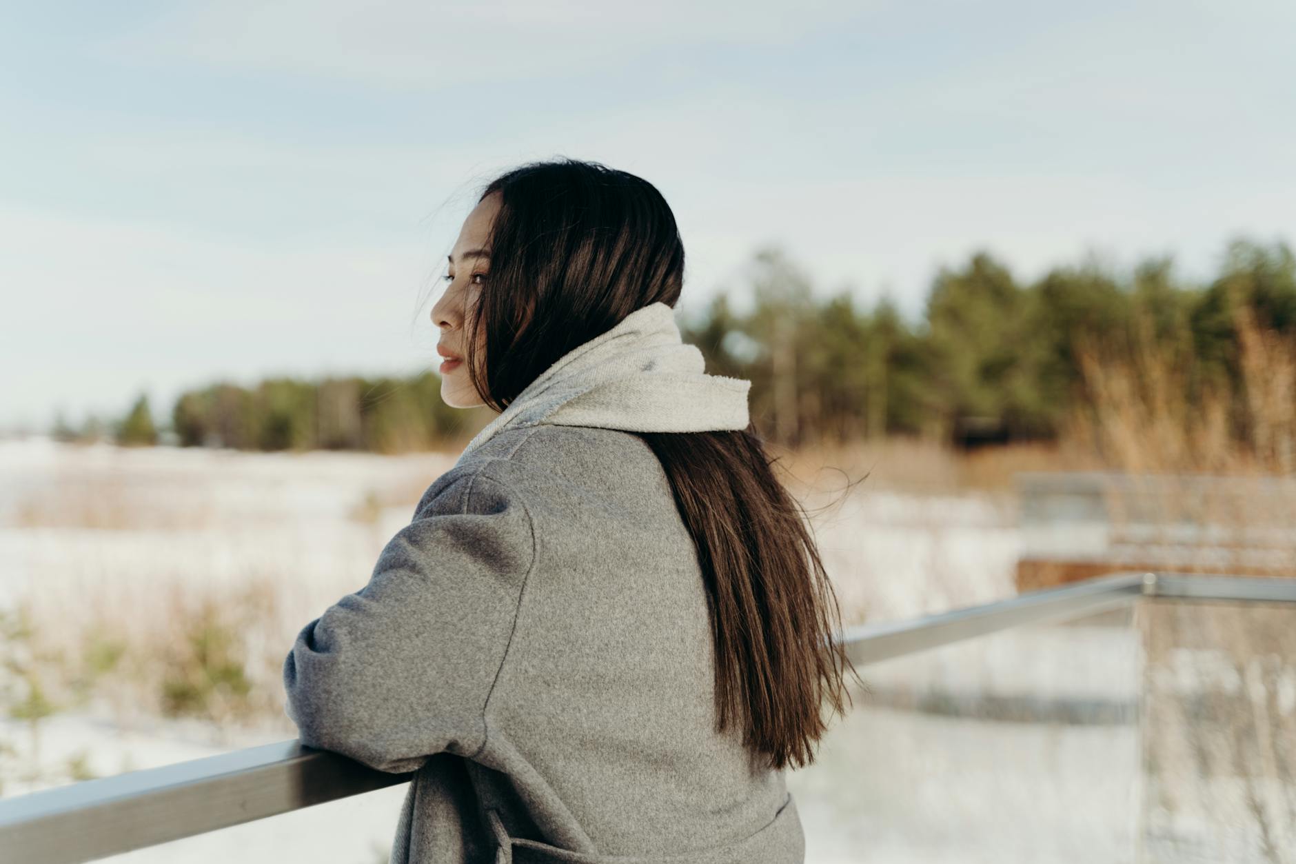 a woman in winter clothing leaning on a metal railing