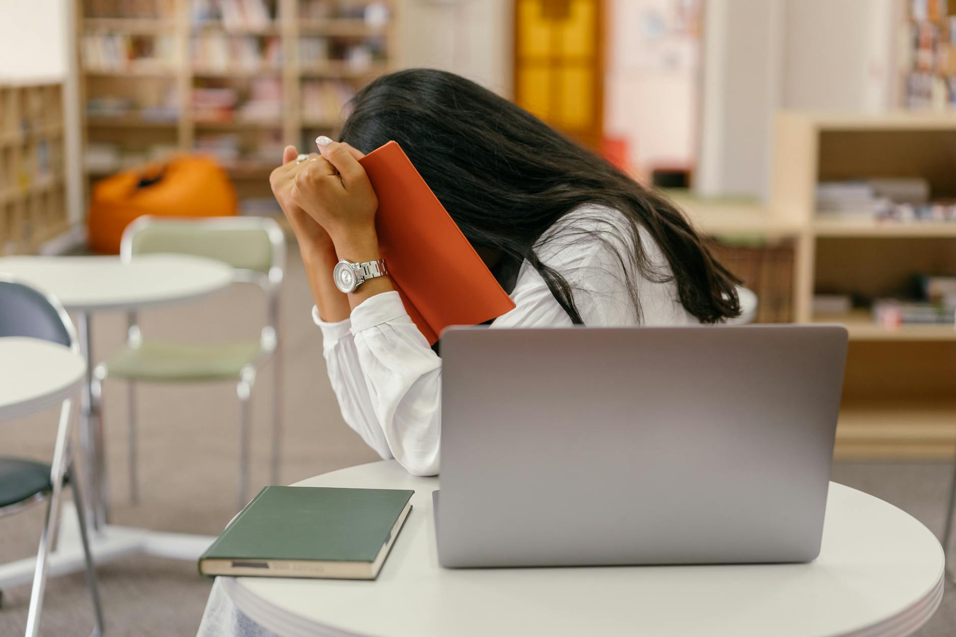 shallow focus photo of woman covering her face with a notebook